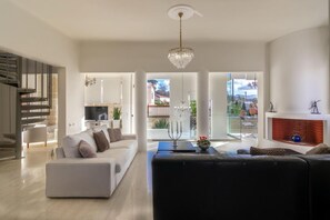 Ein modernes Wohnzimmer mit Treppe, Kamin und Balkon mit Gartenmöbeln.