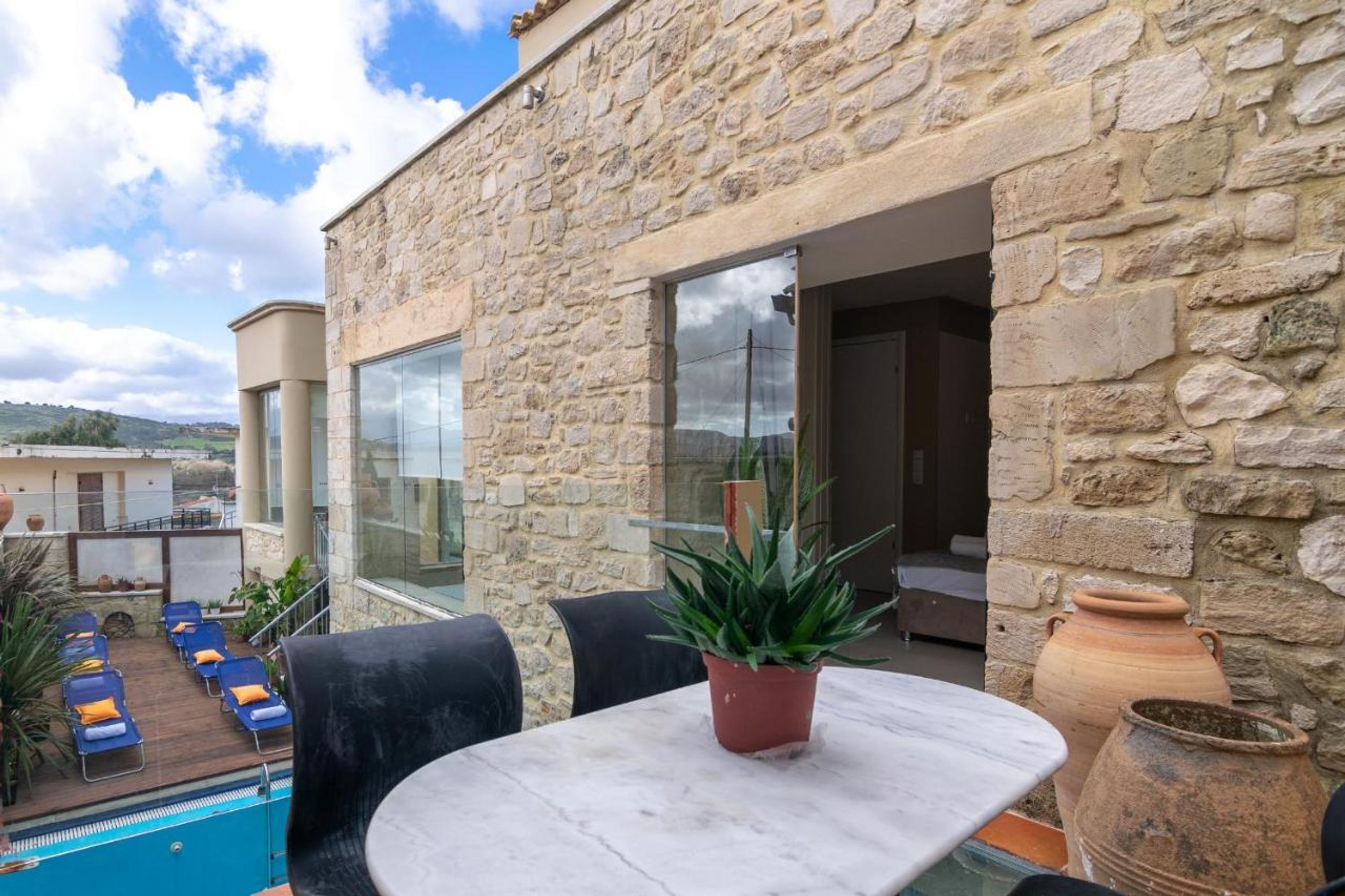 A stone building with a pool, outdoor seating, and a potted plant.