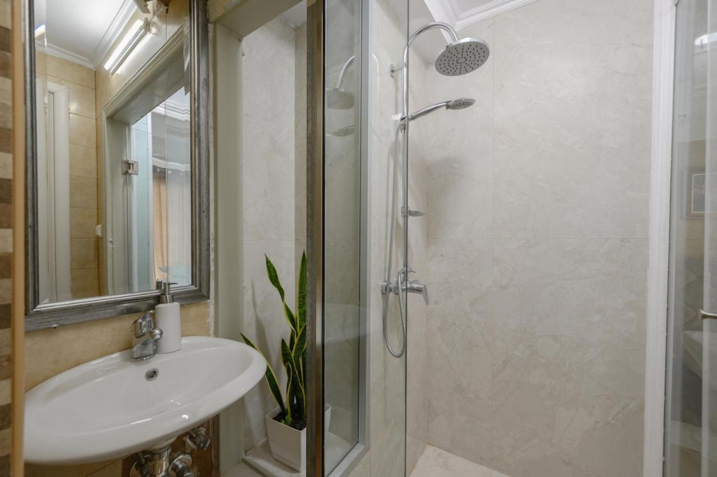 A bathroom with a glass-enclosed shower, a sink, and a mirror.