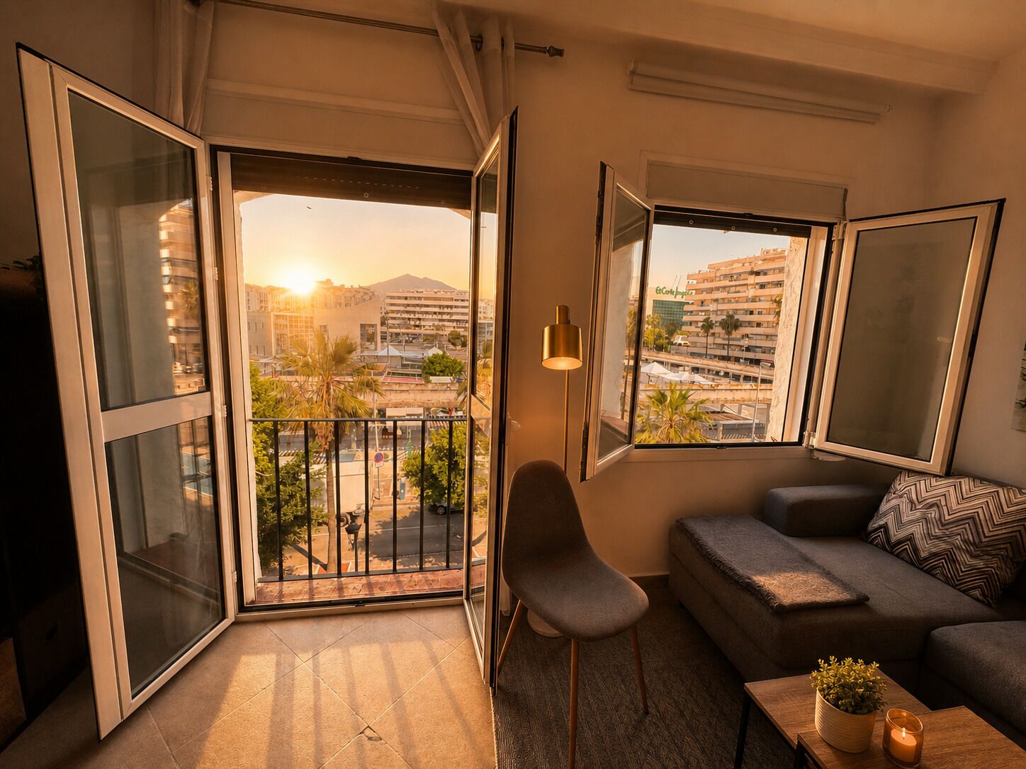 Een moderne woonkamer met balkon, een bank, een fauteuil en een tafel met een kaars.