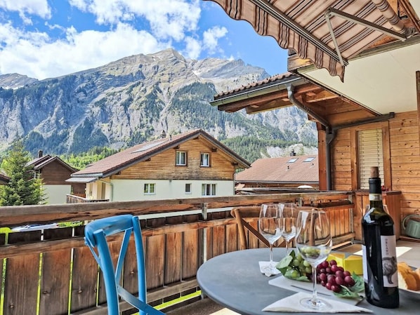 Un chalet en bois doté d’un balcon donnant sur un paysage montagneux.