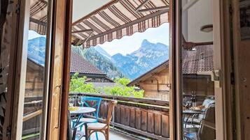 Ein Holzbalkon mit Bergblick, einem Tisch mit Stühlen und einer Glastür.