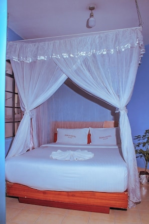 Una cama con dosel, almohadas con texto y una planta en maceta.