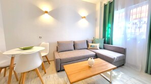 Un salon moderne avec un canapé gris, une table basse en bois et une table à manger blanche avec des chaises.