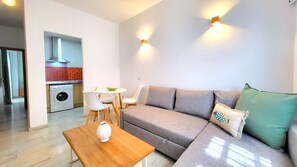Un salon moderne avec un canapé, une table basse en bois et un coin repas avec des chaises.