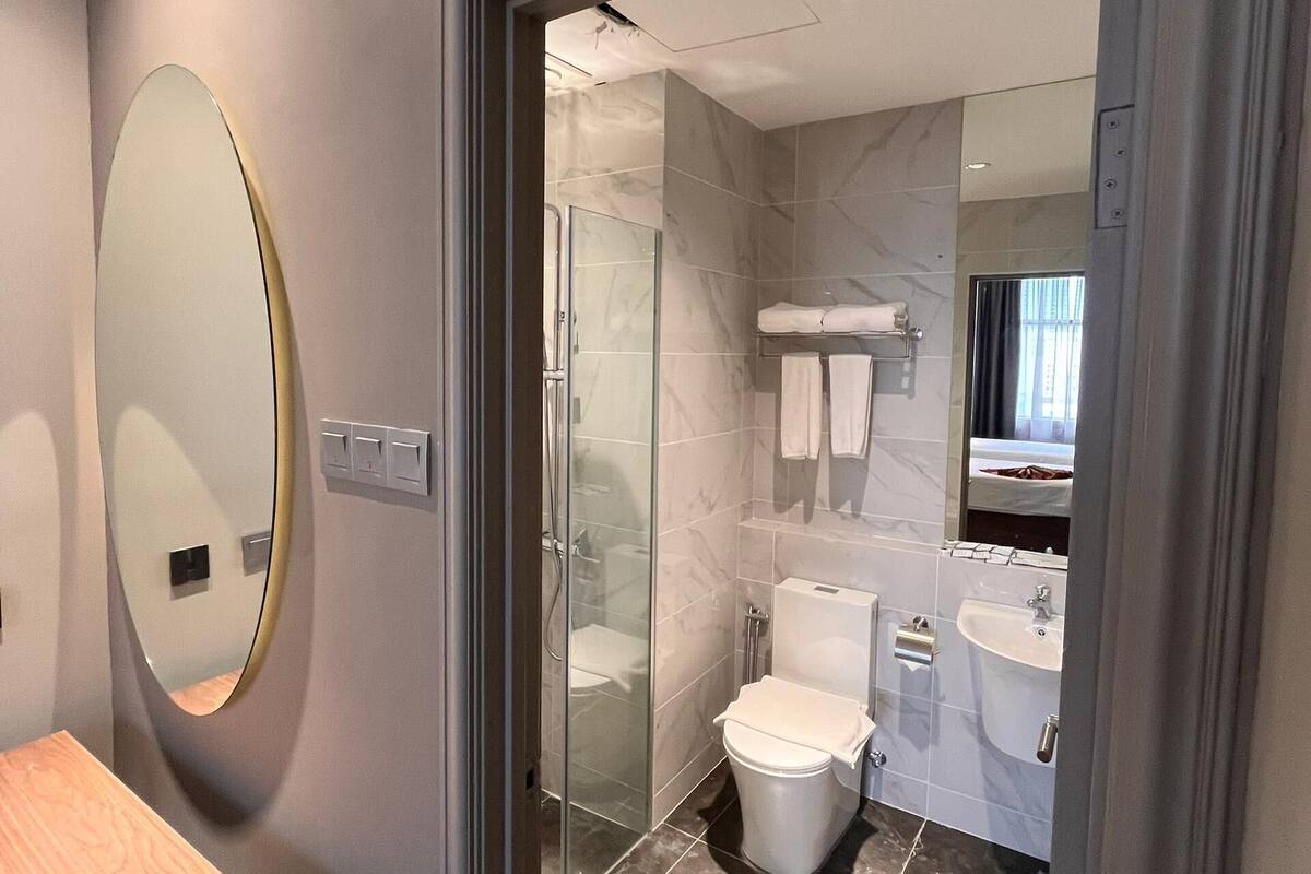 A modern bathroom with a glass shower enclosure, a toilet, a sink, and a mirror.