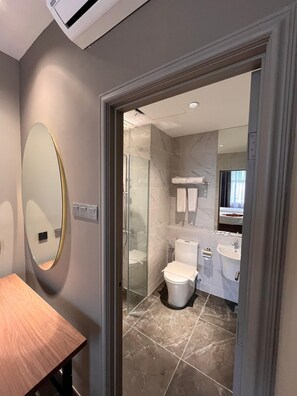 A modern bathroom with a glass shower enclosure, a toilet, a sink, and a mirror. - BRISDALE INTERNATIONAL KUALA LUMPUR (Kuala Lumpur)
