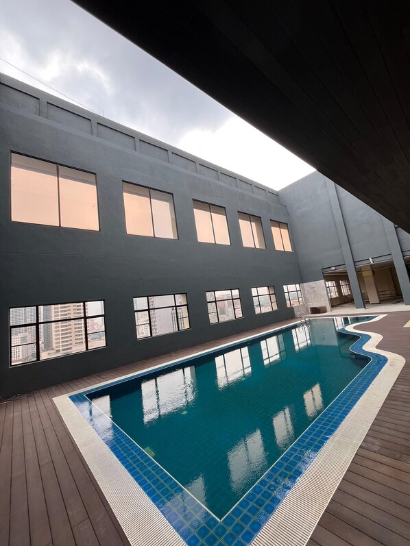 A swimming pool with a wavy edge design, surrounded by a wooden deck. - BRISDALE INTERNATIONAL KUALA LUMPUR (Kuala Lumpur)