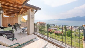 Un espace extérieur abrité, aménagé avec des meubles en osier, une table et offrant une vue sur la mer.