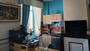 Uma cozinha compacta com micro-ondas, cafeteira e um pequeno espaço de refeições com mesa e cadeiras.