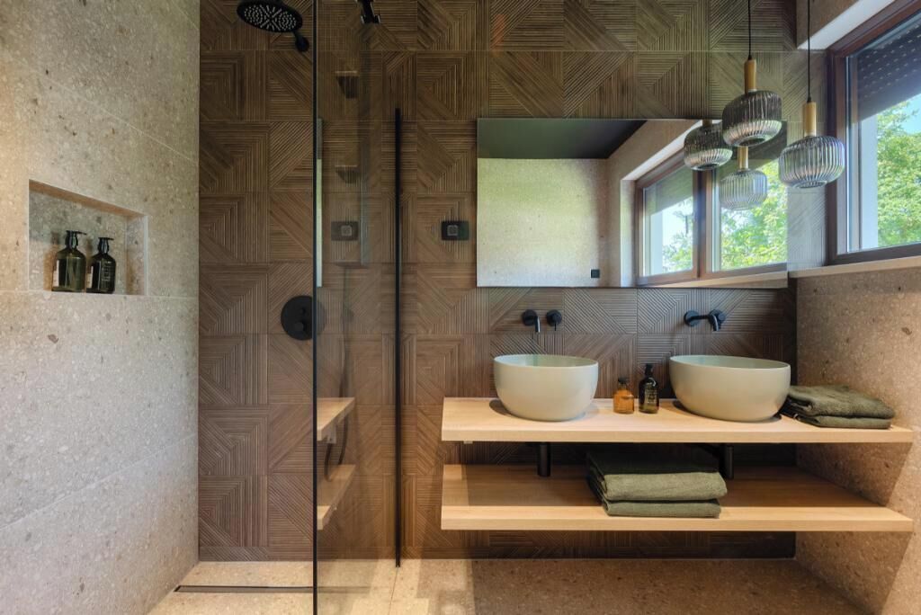 Une salle de bain moderne avec un grand miroir, deux lavabos et un espace douche.