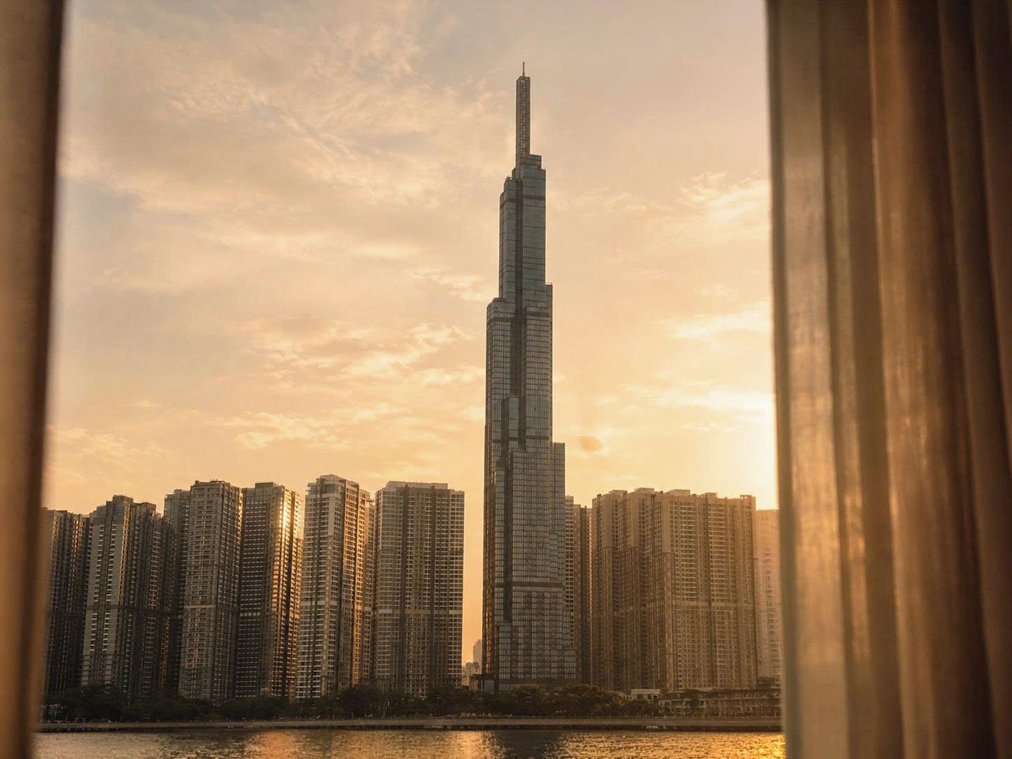 Un grattacielo dal design particolare e slanciato, circondato da altri edifici alti, visto da lontano.