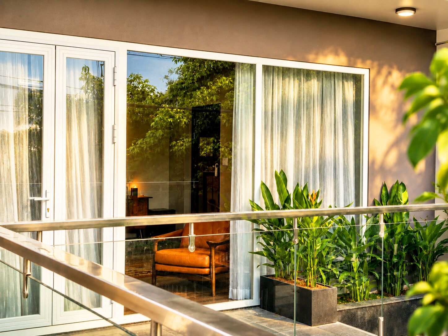 Un interno moderno con una porta vetrata che conduce a un balcone, una sedia di legno e piante in vaso.