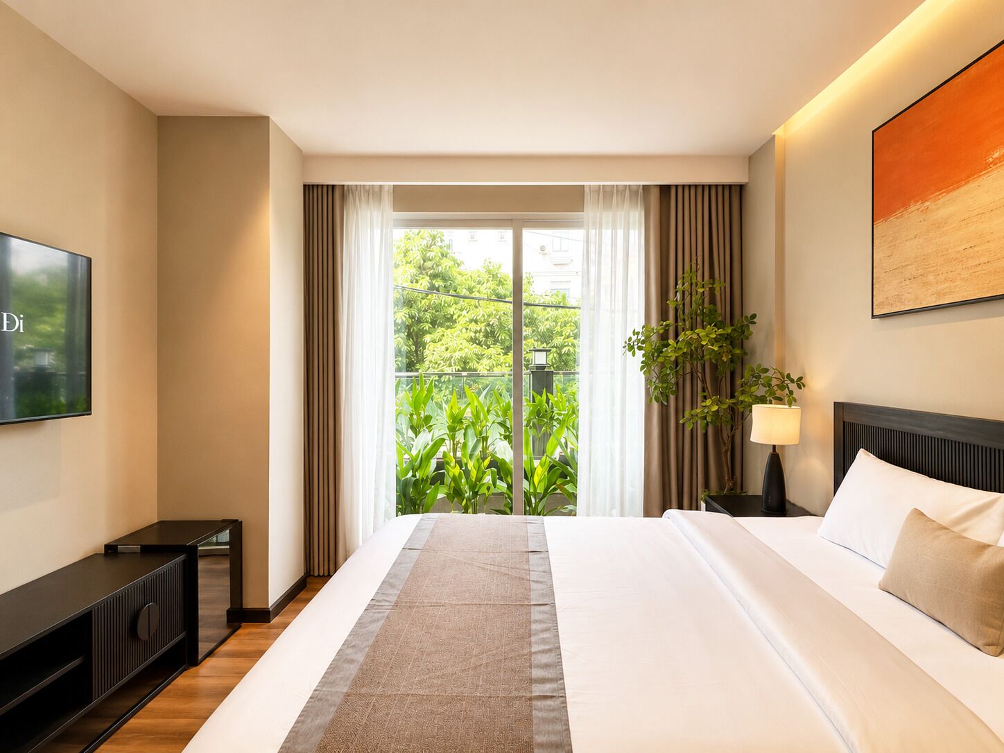 A hotel room with a bed, a TV, a plant, and a view of greenery outside.