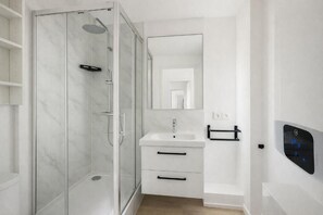 Une salle de bain moderne avec une douche à parois de verre, un lavabo blanc et un miroir au-dessus.