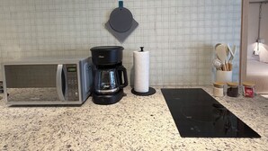 A kitchen with a coffee maker, paper towel holder, microwave, and a black mat on the counter. - Modern 1BR in Juárez with fast WiFi, great natural light, a comfortable queen bed, a fully equipped kitchen, and a luxury bathroom. Perfect for couples or solo travelers seeking comfort, style, and a prime location in Mexico City. (Cuauhtémoc)
