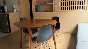 A dining area with a wooden table and chairs, a kitchen area with a refrigerator, and a wooden partition with shelves. - Modern 1BR in Juárez with fast WiFi, great natural light, a comfortable queen bed, a fully equipped kitchen, and a luxury bathroom. Perfect for couples or solo travelers seeking comfort, style, and a prime location in Mexico City. (Cuauhtémoc)