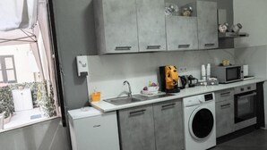 Una cocina moderna con armarios grises, lavadora, microondas y un lavamanos.