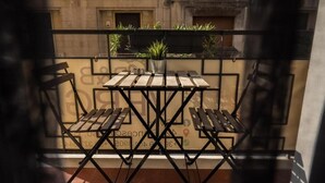 Un balcón con una mesa, sillas, una planta en maceta y vista a un edificio.
