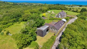 Ein ländliches Anwesen mit einer großen Scheune, einem Haus und Blick auf das Meer.