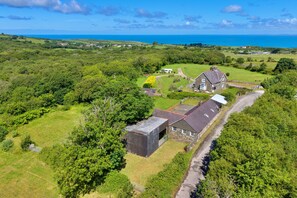 Ein ländliches Anwesen mit einer großen Scheune, einem Haus und Blick auf das Meer.