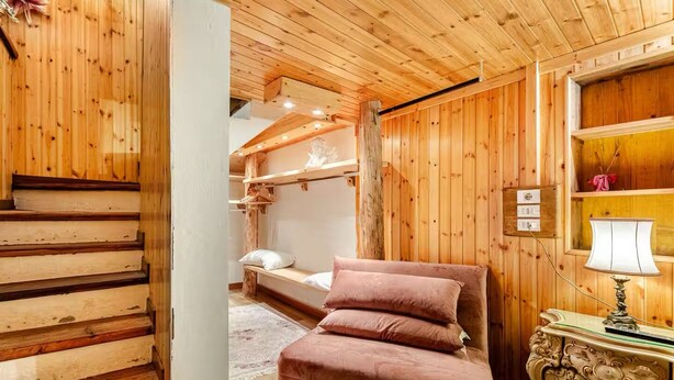 Um interior de madeira com uma cama, um abajur e uma escada.