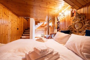 A wooden interior with a bed, pillows, a chandelier, and a staircase. - [Courmayeur City Center] Imperial Elegance (Courmayeur)