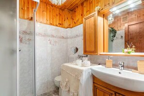 A bathroom with wooden paneling, a white sink, a mirror, and a toilet. - [Courmayeur City Center] Imperial Elegance (Courmayeur)