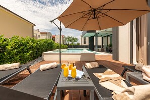 Ein Poolbereich mit Liegestühlen, einem Sonnenschirm und einem Tisch mit Getränken.