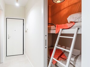 Ein Zimmer mit einem Etagenbett, einer weißen Tür und einer Leiter.