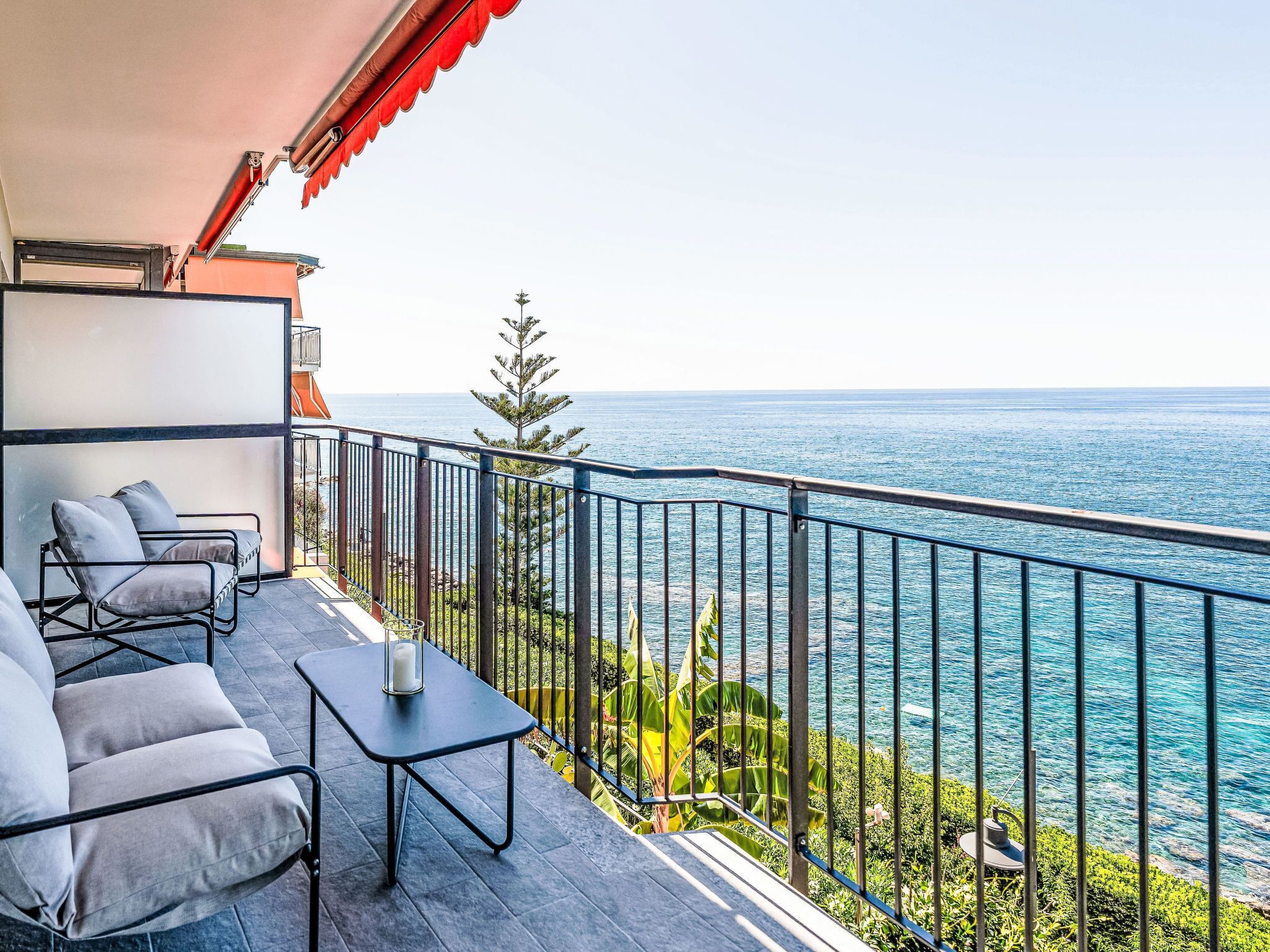 Un balcon avec vue sur la mer, une table et deux chaises.