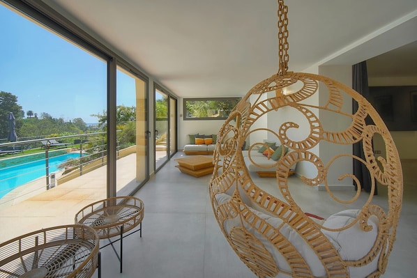 Ein Balkon mit Pool, Korbmöbeln und einer Hängematte.