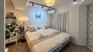 Ein modernes Schlafzimmer mit einem Bett, Nachttischlampen, einem gerahmten Bild und einem Blumentopf.