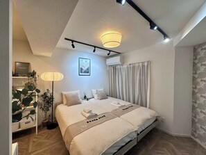 Ein modernes Schlafzimmer mit einem Bett, Nachttischlampen, einem gerahmten Bild und einem Blumentopf.