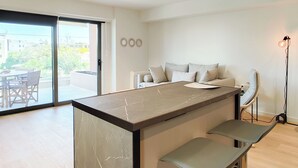 Una cocina moderna con encimera de mármol, banco empotrado y puerta corredera de vidrio que da a un espacio exterior.