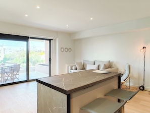A modern kitchen with a marble countertop, a built-in bench, and a sliding glass door leading to an outdoor area. - Boutique Riviera Stay in Voula Center (Voula)