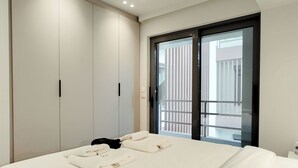 Un dormitorio con cama, armario y puerta corrediza de vidrio a un balcón.
