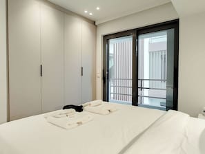 A bedroom with a bed, a wardrobe, and a sliding glass door to a balcony. - Boutique Riviera Stay in Voula Center (Voula)