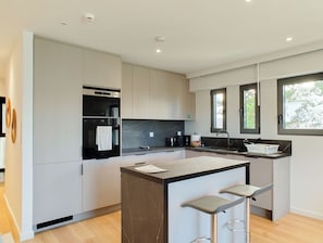 A modern kitchen with a central island, bar stools, a built-in oven, and a window with a view. - Boutique Riviera Stay in Voula Center (Voula)