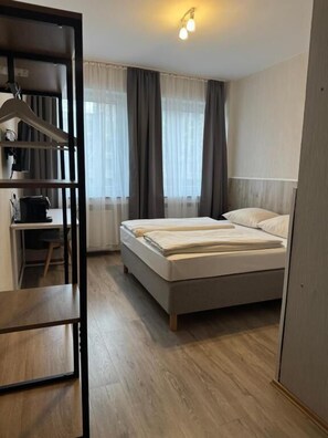 A bedroom with a bed, a desk, and a wardrobe. - Hotel Allee 55 (Hannover)