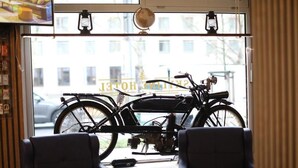 A room with a bicycle, a window with a view of a building, and two chairs. - Hotel Allee 55 (Hannover)