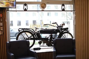 Una habitació amb una bicicleta, una finestra que dona a un edifici i dues cadires.