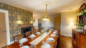 A dining room with a long wooden table set for a meal, a fireplace, and a chandelier.