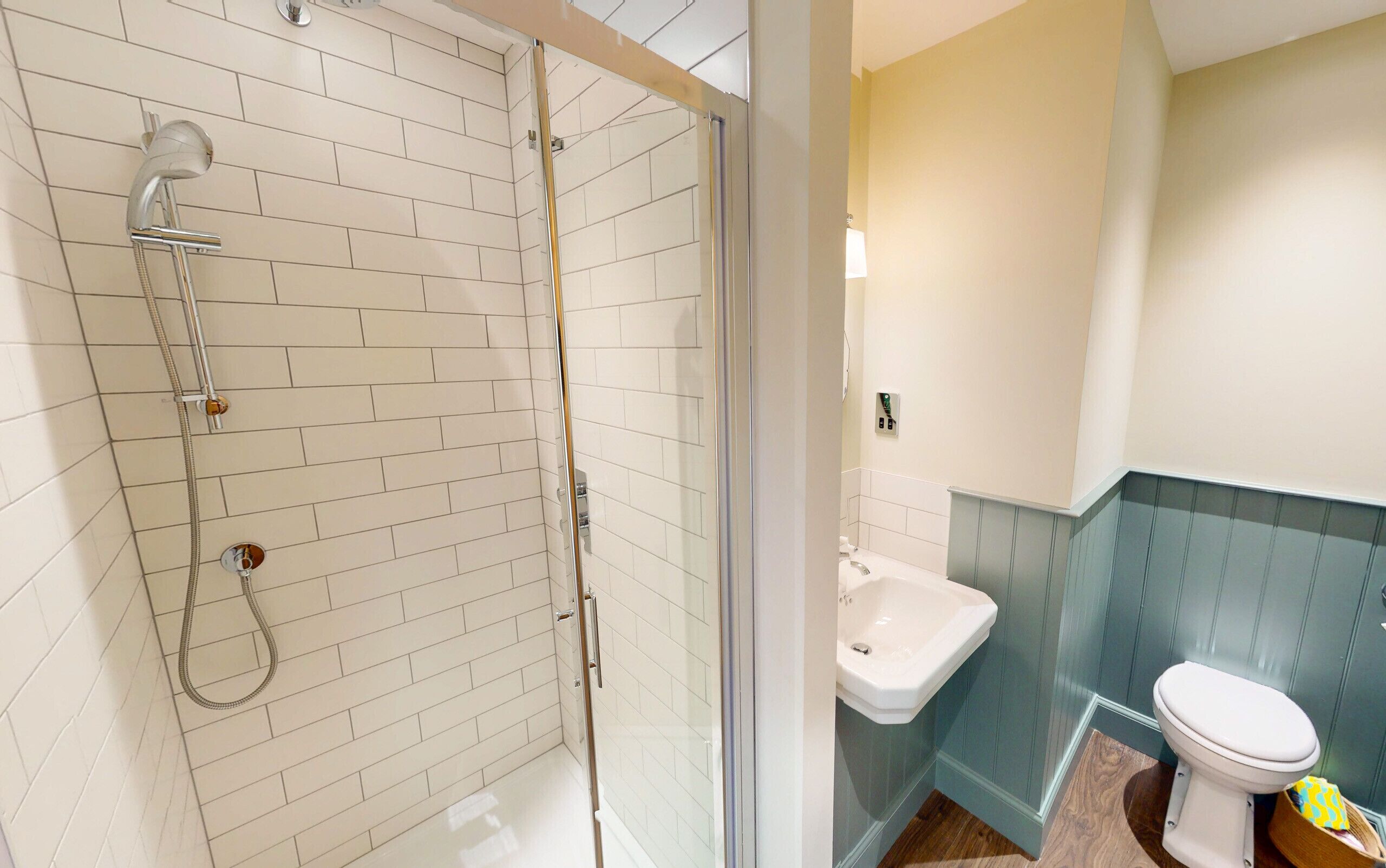 Un baño con ducha de vidrio, un lavabo blanco y un inodoro.