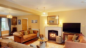 A living room with a fireplace, sofa, television, and decorative items.