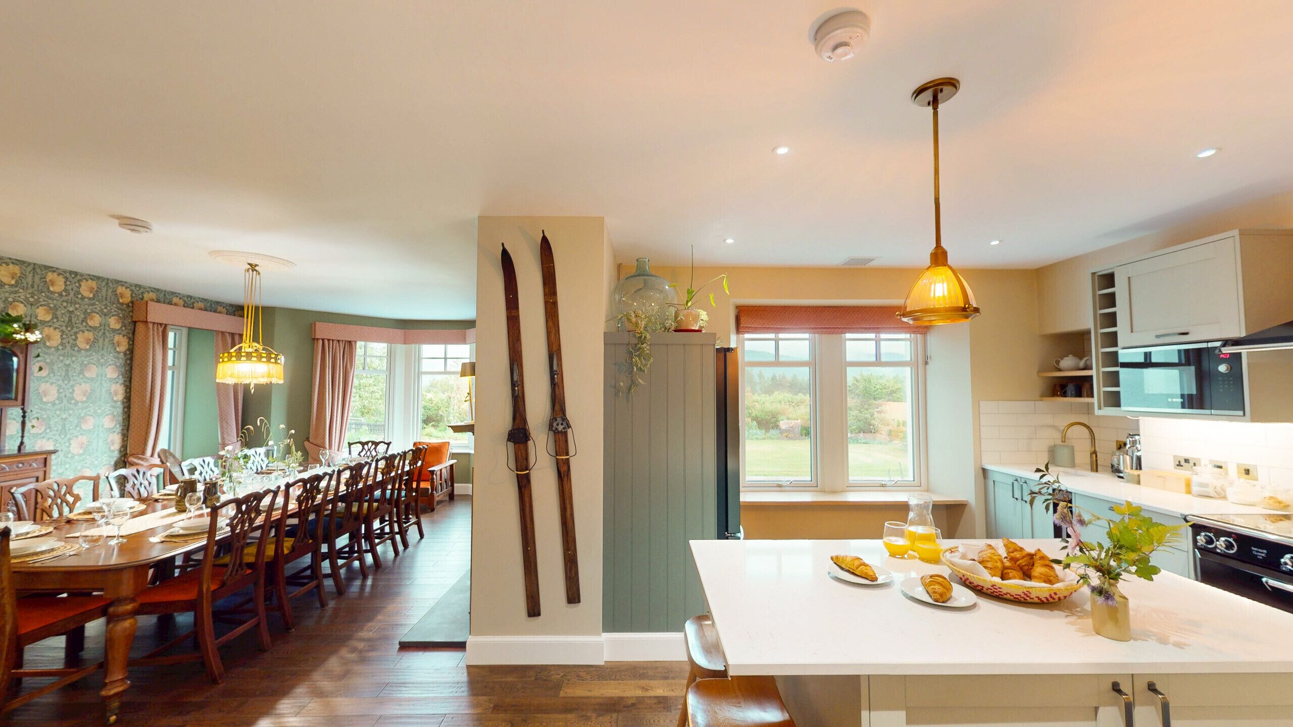 Un comedor con una mesa y sillas de madera, una cocina con electrodomésticos modernos y vistas al exterior.