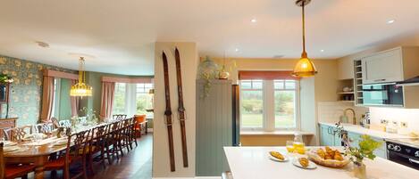 Un comedor con una mesa y sillas de madera, una cocina con electrodomésticos modernos y vistas al exterior.
