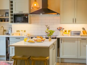 A modern kitchen with a central island, stainless steel appliances, and a ProCook toaster.