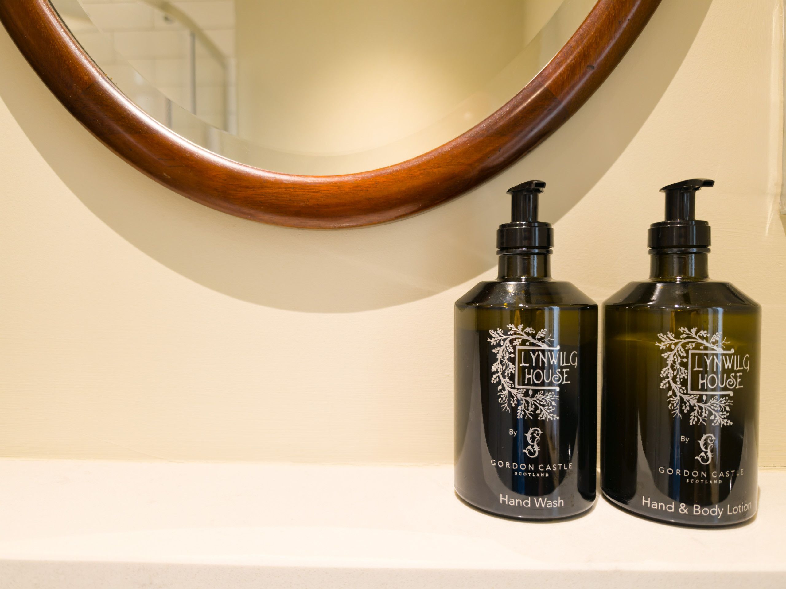 Deux flacons de savon pour les mains et une lotion pour les mains et le corps de la marque Lynwlg House, posés sur une surface blanche.
