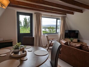 A cozy living room with a round table, a brown leather sofa, and a TV.
